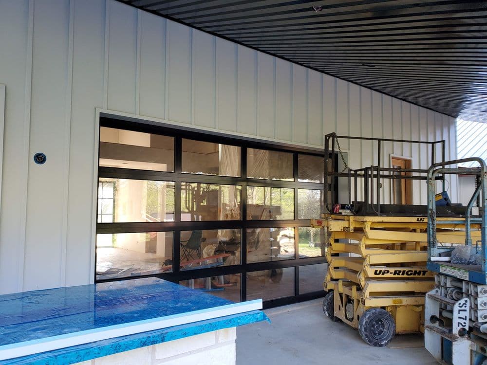 Modern building exterior with large black framed windows and construction equipment.