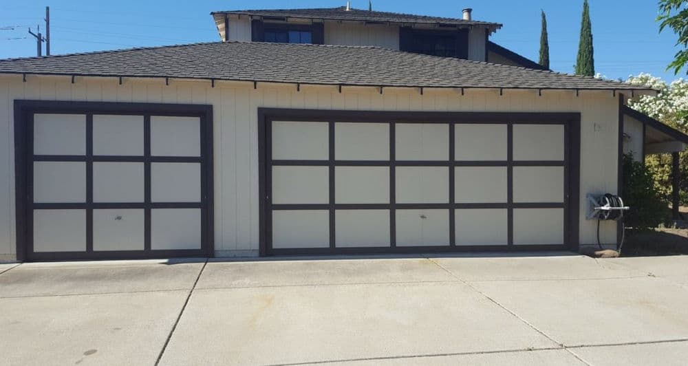 Modern residential garage with two large doors and a concrete driveway in a suburban setting.