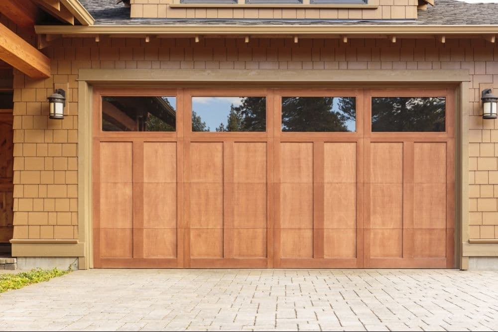 Wooden garage door featuring large windows, designed for a modern home.