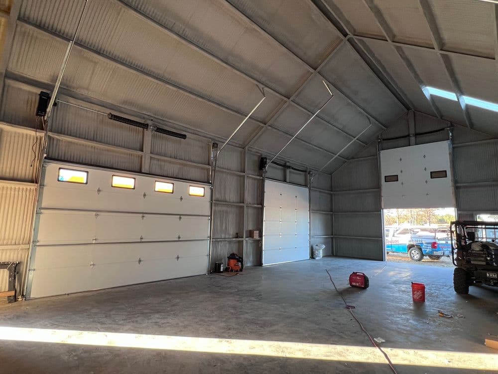 Spacious garage interior with two large doors, concrete floor, and natural light.