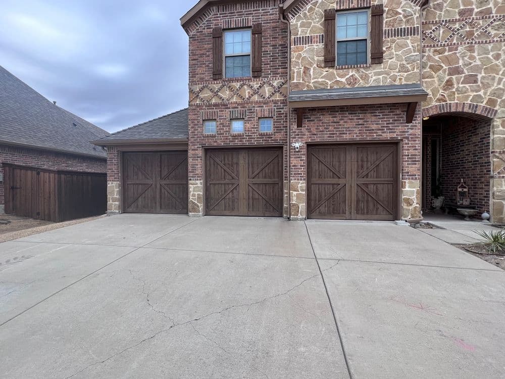 Modern home exterior featuring a stone and brick facade with wooden garage doors.