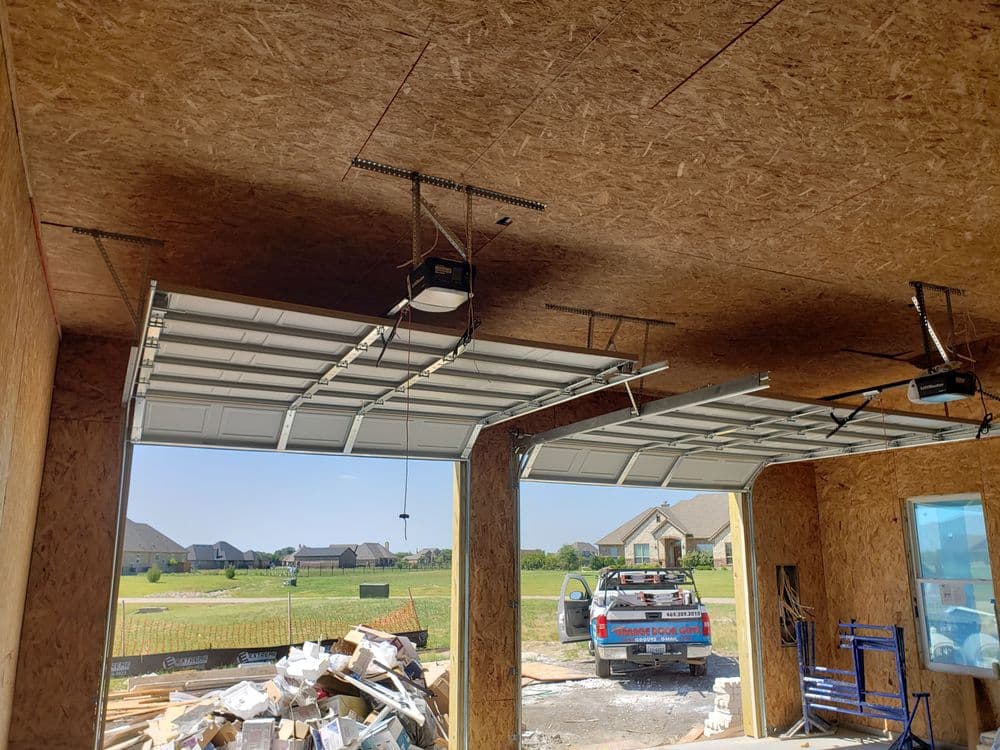 Interior of an unfinished garage with open doors, construction debris, and a parked truck outside.