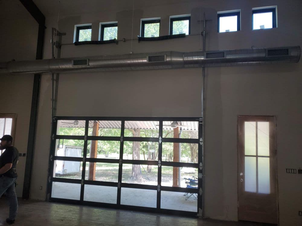 Modern industrial interior with a large glass garage door and ambient natural light.