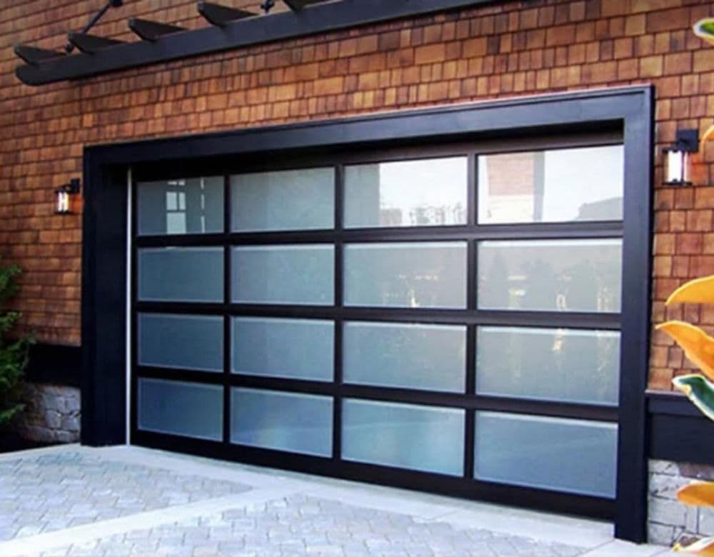 Modern black frameless garage door with glass panels and wooden wall background.
