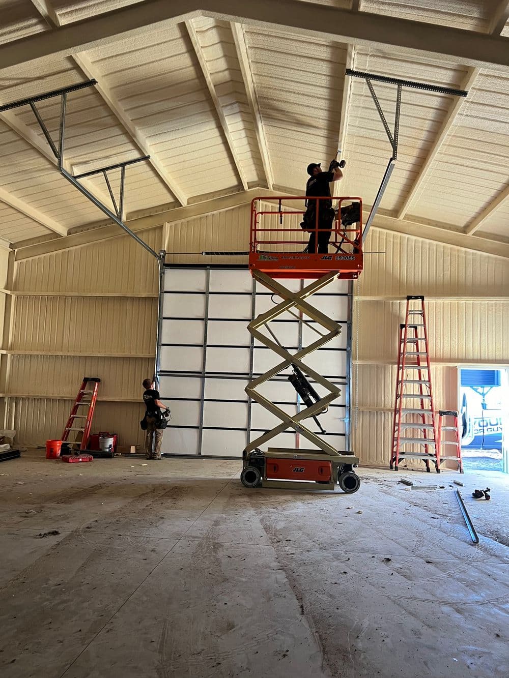 Workers installing equipment from a scissor lift in a spacious warehouse.