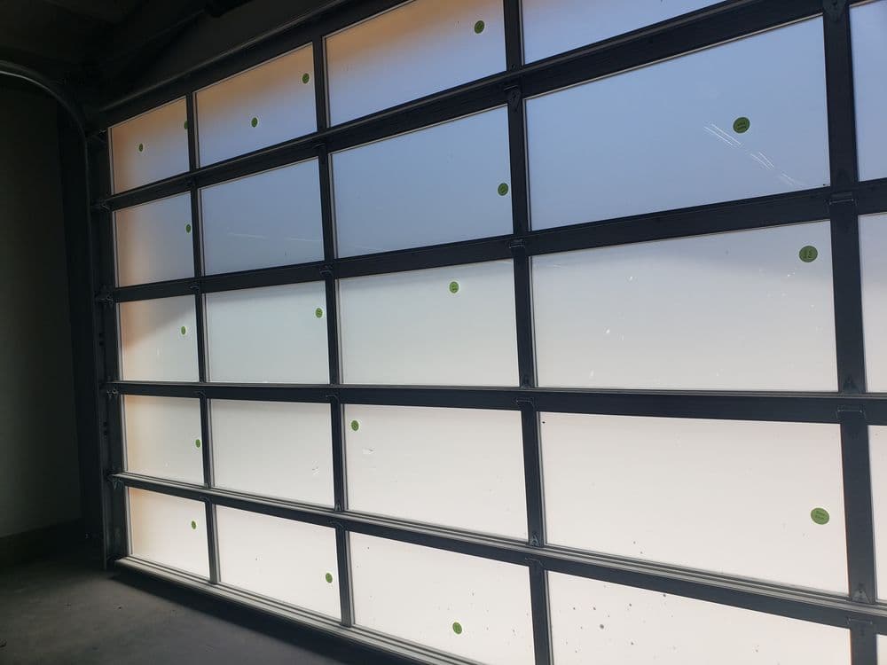 Frosted glass garage door with green dots and natural light filtering through.